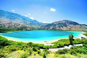 A coastal landscape with a large turquoise bay, surrounded by green hills and mountains. - Minoas Sea Villa Heated Pool (Lake Kournas)