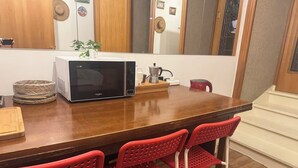 Een keuken met een magnetron, een koffiezetapparaat en rode stoelen.
