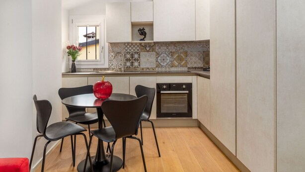 A modern kitchen with a round table, black chairs, a red vase, and a tiled backsplash. - A comfortable and welcoming 30 square meters studio apartment, perfect for three people, located on the fourth floor of a renovated building (no elevator).The property is situated in the heart of Modena (within the ZTL restricted traffic zone); it is an  (Modena)