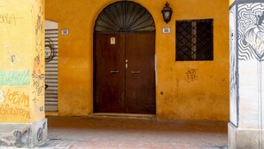 A building entrance with a brown double door, a number '56' sign, and a small window with a metal grid. - A comfortable and welcoming 30 square meters studio apartment, perfect for three people, located on the fourth floor of a renovated building (no elevator).The property is situated in the heart of Modena (within the ZTL restricted traffic zone); it is an  (Modena)