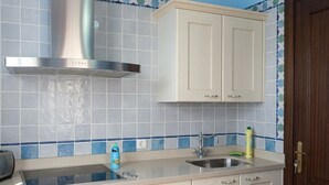 Una cocina con campana extractora de acero inoxidable, un lavamanos y armarios de colores claros.