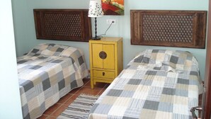 Una habitación con dos camas, una mesita de noche, una lámpara y un cuadro en la pared.