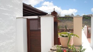 Un edificio blanco con puerta de madera, un camino de piedra y una planta en maceta.