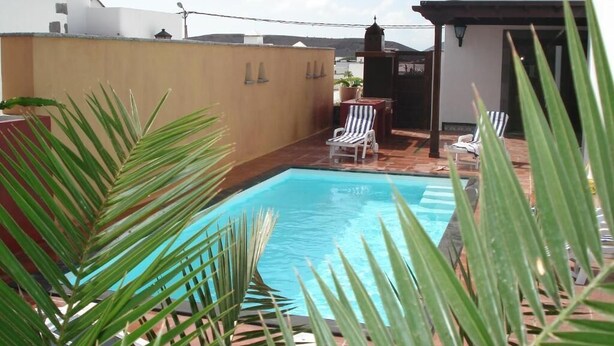 Una piscina con sillones de descanso, una pérgola y vistas del entorno.