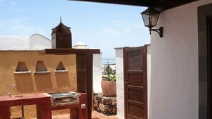 Un patio al aire libre con una parrilla, una planta en maceta y una puerta.