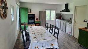 Una cuina moderna amb zona de menjador, armaris verdosos i una màquina de cafè, a més d'un gran finestral.