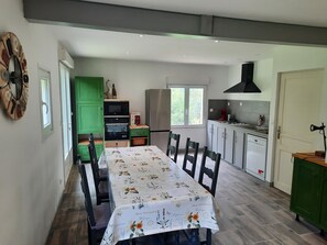 Eine moderne Küche mit Essbereich, grünen Schränken, einer Kaffeemaschine und einem großen Fenster.
