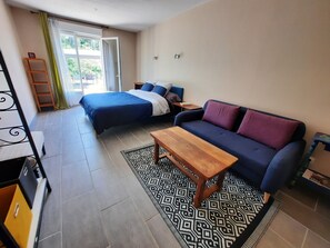 Ein Zimmer mit einem Bett, einer Couch, einem Holztisch und einem gemusterten Teppich.