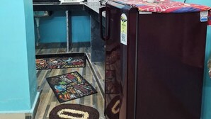 Una cocina compacta con cafetera, refrigerador y planta en maceta.