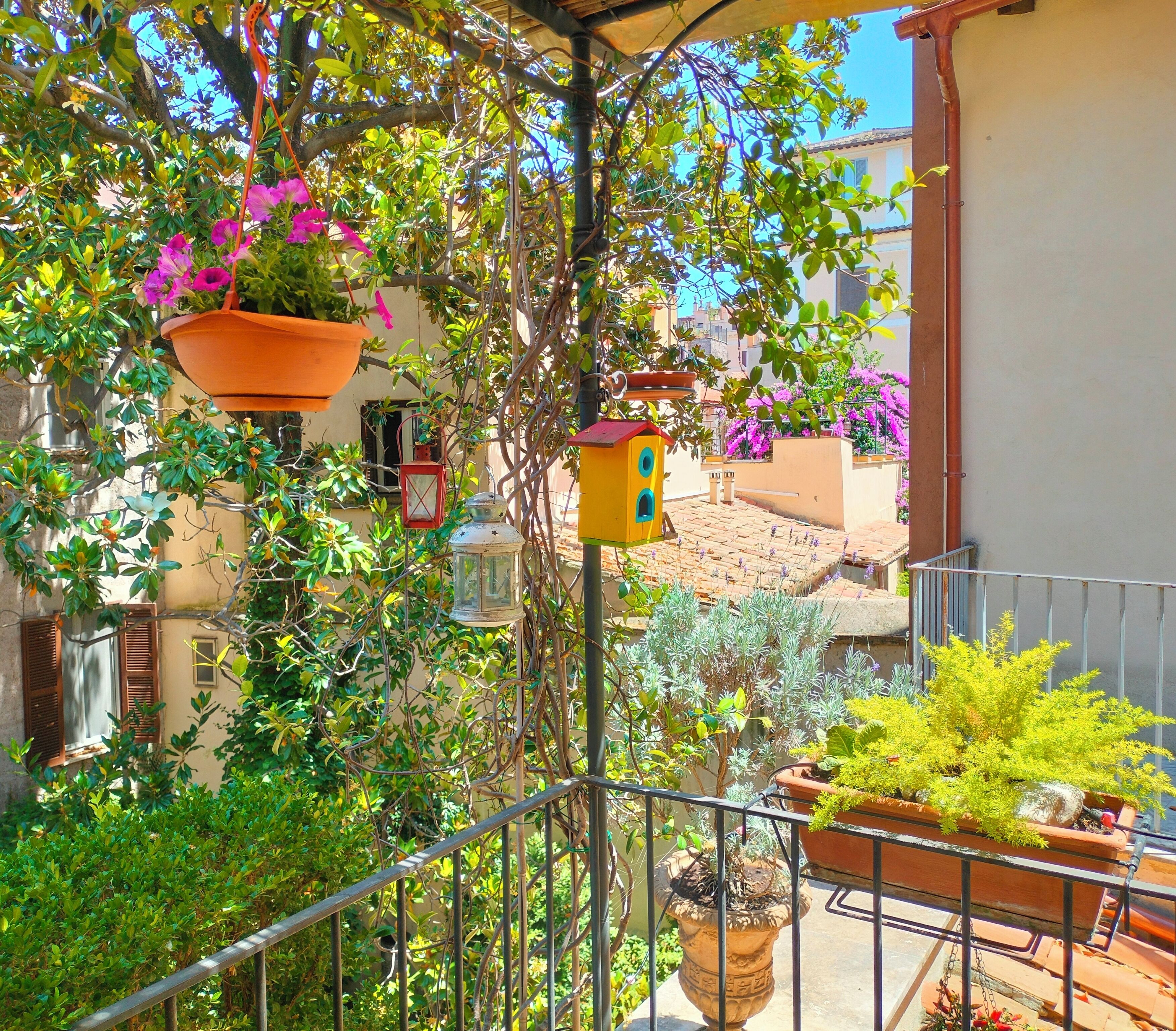 A balcony with potted plants, a birdhouse, and a hanging lantern.