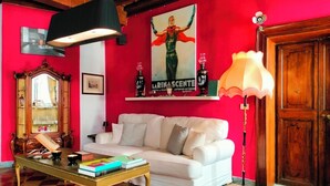 Un salon avec un canapé blanc, une table basse en bois, un mur rouge, un grand miroir et une porte en bois.