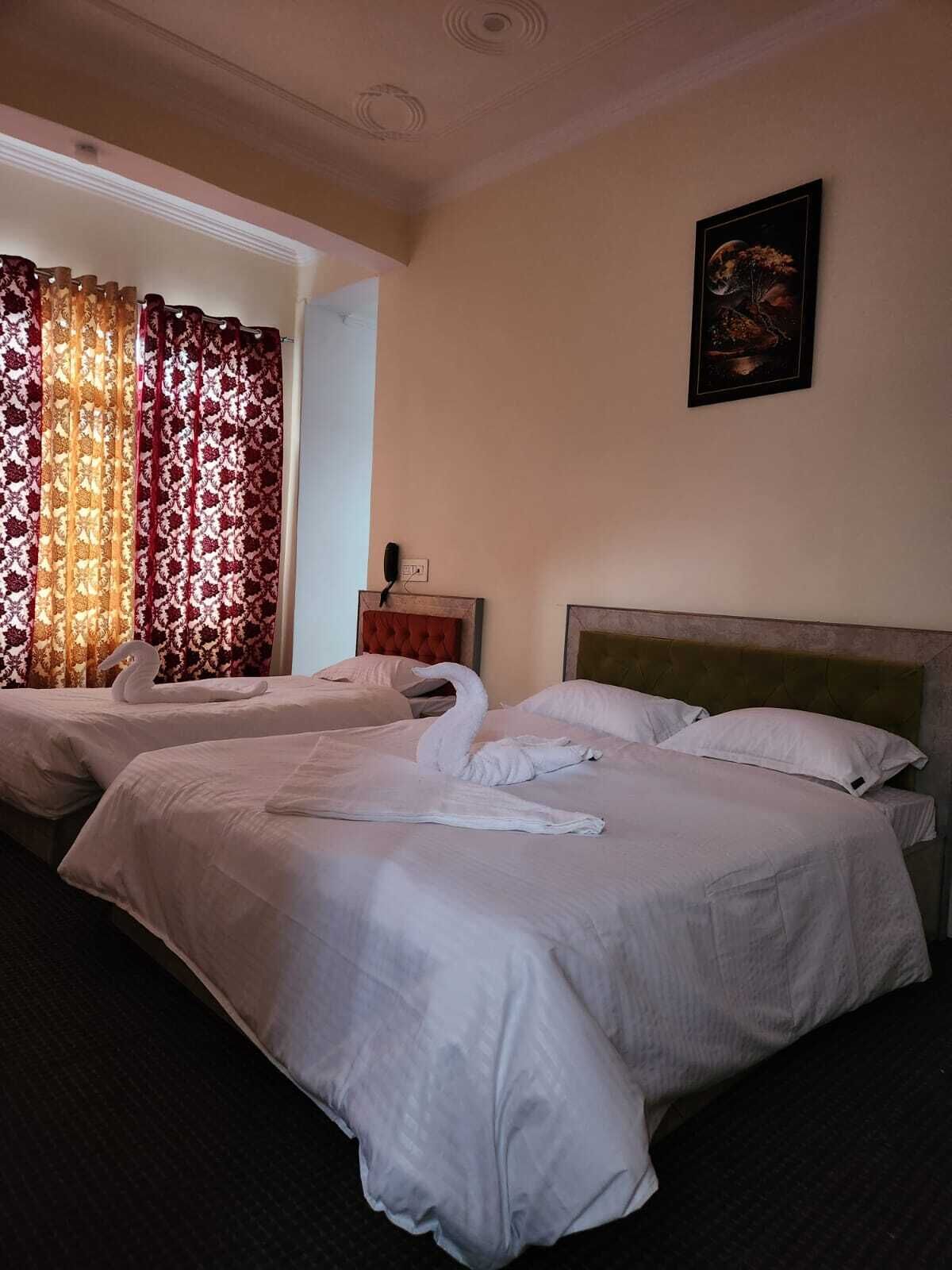 Habitación de hotel con dos camas, cabecera, un cuadro en la pared y cortina con estampado floral.