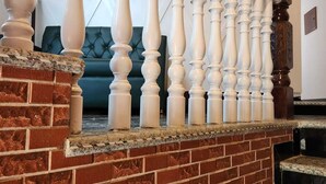 Una escalera con balaustres blancos y un muro de ladrillo.