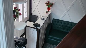 Un espacio de oficina moderno con un escritorio, un sofá verde, una pared decorativa y un techo con estampado.