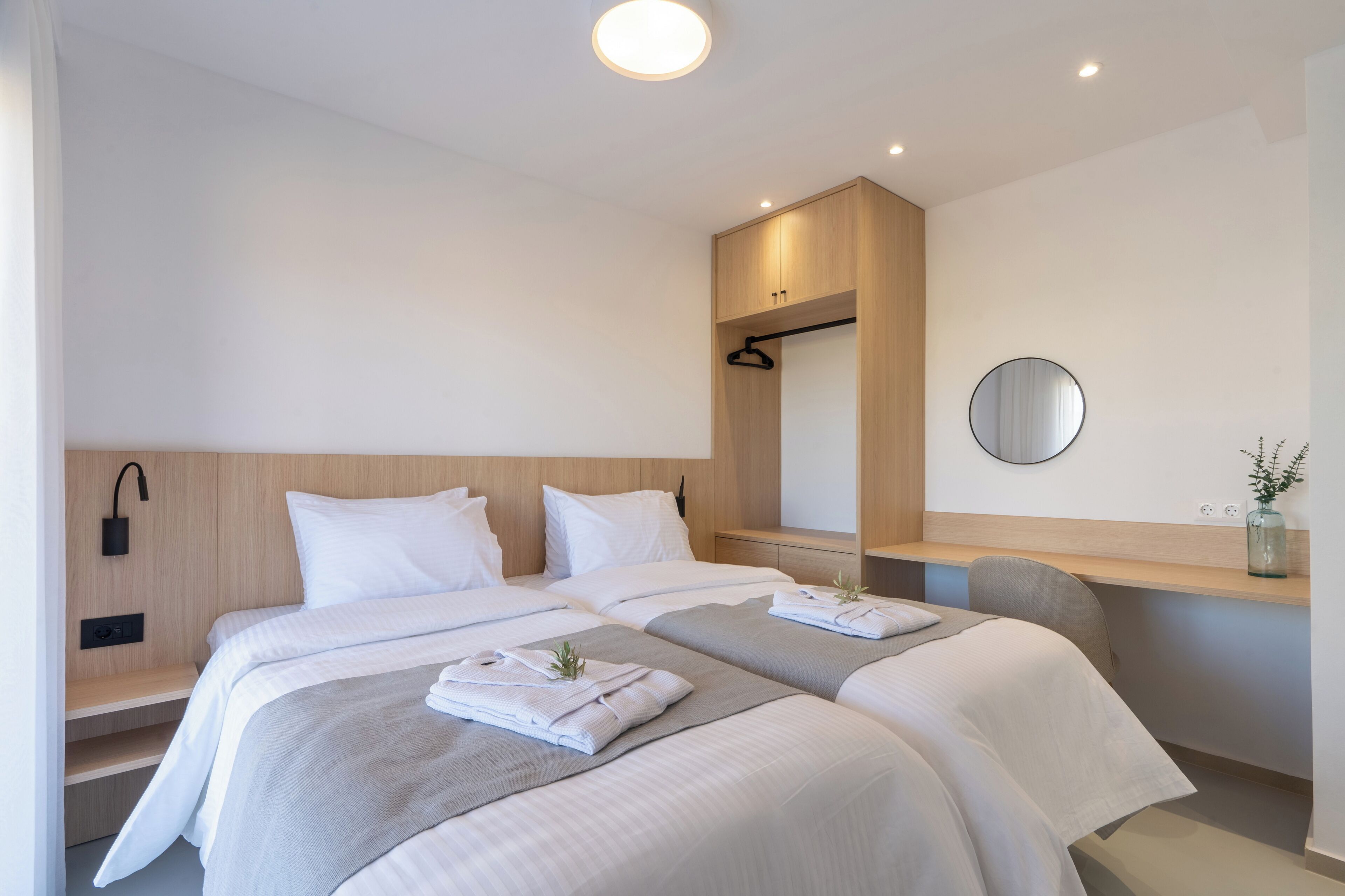 Ein modernes Hotelzimmer mit einem großen Bett, Nachttischen, einem Spiegel und einer kleinen Schreibtischzeile.