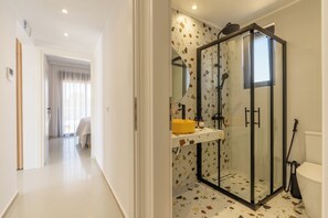 Une salle de bain moderne avec une douche à parois de verre, un lavabo jaune et des toilettes.