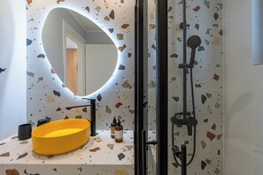 A bathroom with a round mirror, a yellow sink, and a shower area. - Notias- An Intimate Comfort Stay with Garden and Pool (Kokkini Hani)