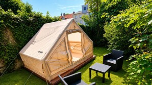 A tent with a canopy, a small table, and two chairs in a grassy backyard.