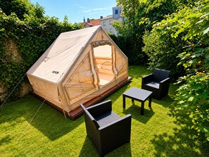 A tent with a canopy, a small table, and two chairs in a grassy backyard. - Glamping Nature & Évasion in Boulogne-sur-Mer (Boulogne-sur-Mer)
