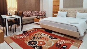 Habitación de hotel con cama, escritorio, silla, sofá y alfombra estampada.