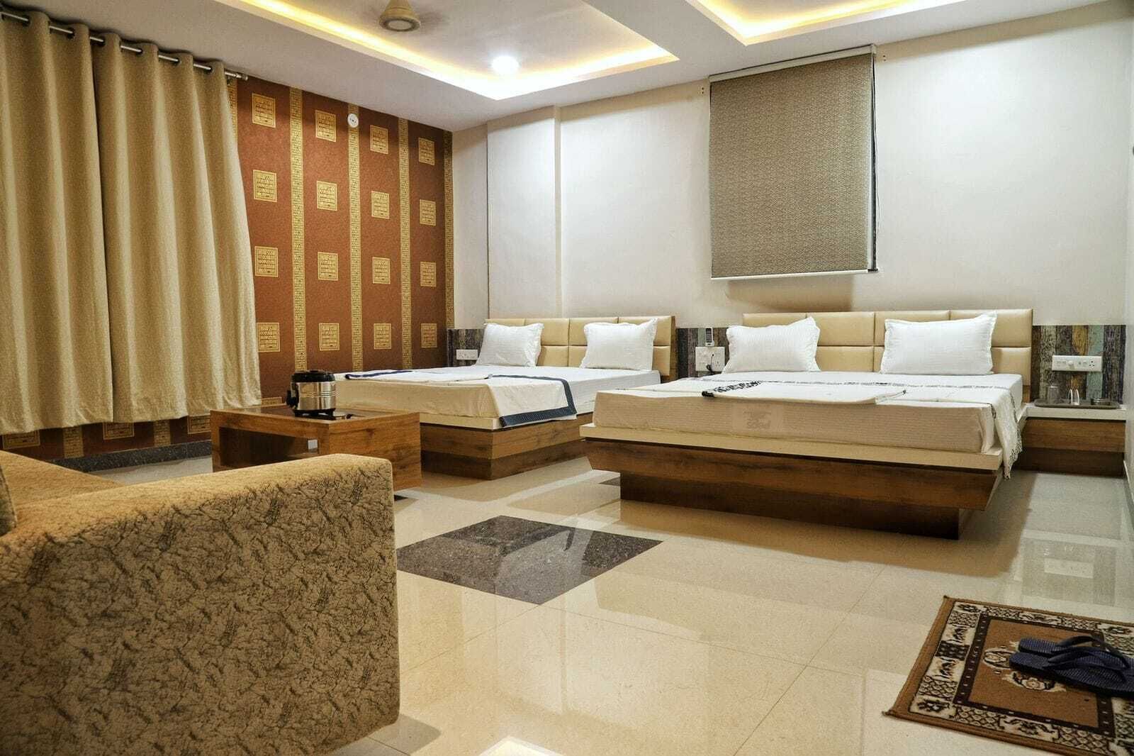 Une chambre d’hôtel avec deux lits, un canapé, une table basse et un tapis décoratif.