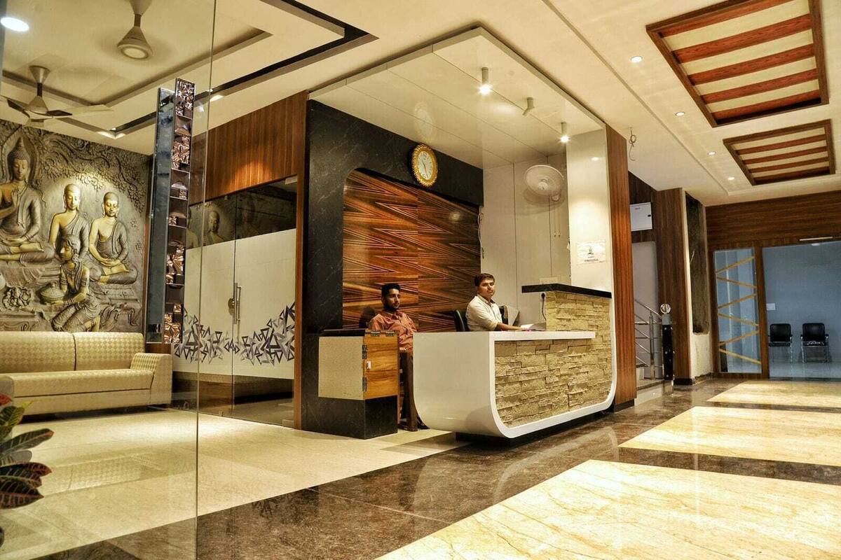 A reception area with a receptionist desk, a sofa, a wall with a Buddha mural, and a clock.