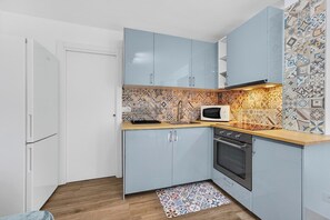 A compact kitchen with light blue cabinets, a microwave, and patterned backsplash tiles. - Vista Marina Seaside Comfort (Santa Cruz de Tenerife)
