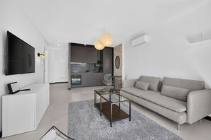A modern living room with a grey sofa, a glass coffee table, and a flat-screen TV mounted on the wall. - Fabulous brand new apartment in Parque Royal (Costa Adeje)