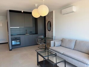 A modern kitchen with a built-in oven, a dining area with a glass table and chairs, and a living area with a sofa and a coffee table. - Fabulous brand new apartment in Parque Royal (Costa Adeje)