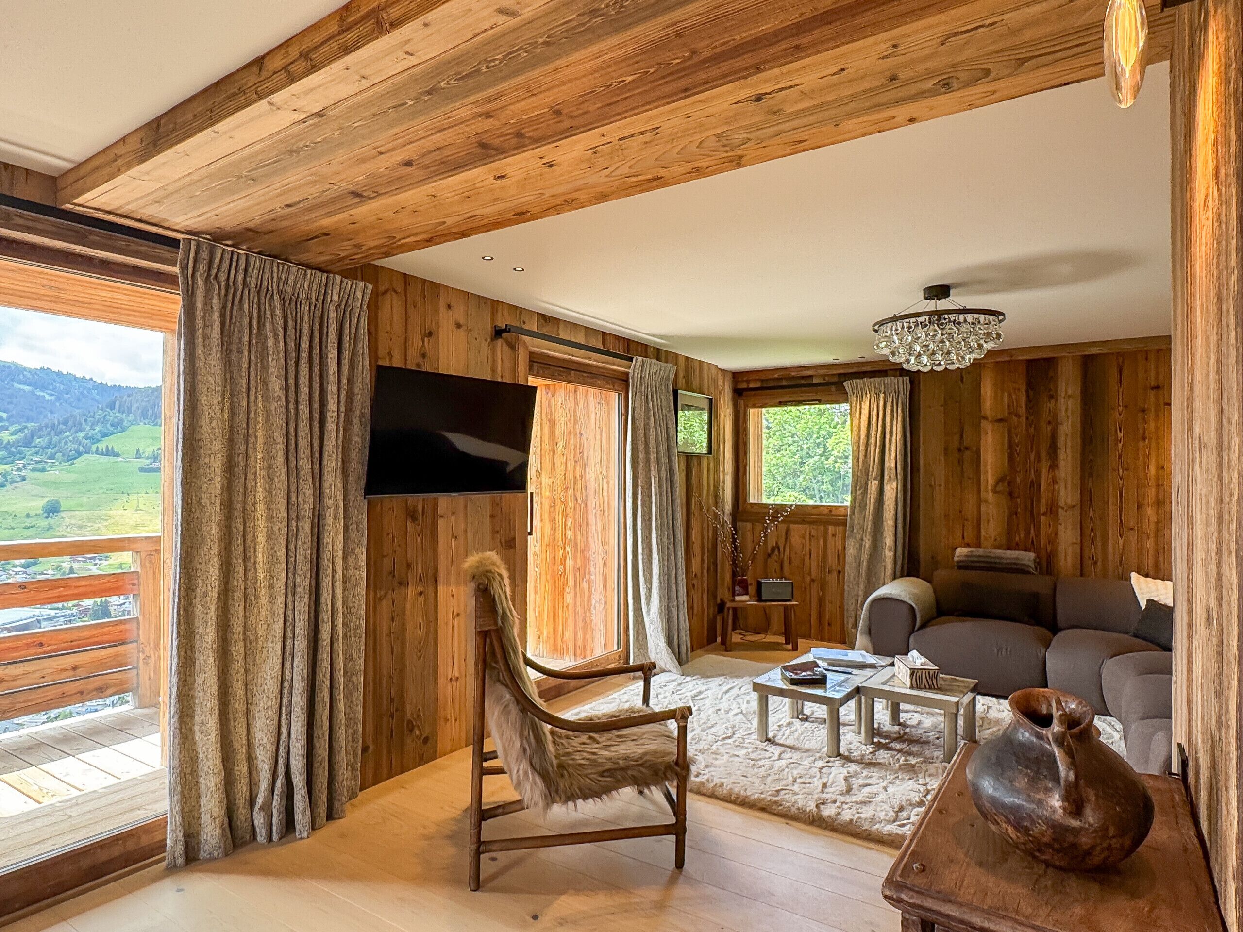 A wooden interior with a TV, sofa, and a view of the outdoors.