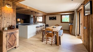 A wooden interior with a kitchen, dining area, and large windows. - Coeur de Mage: Stunning View of Megève (Megève)