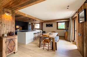 A wooden interior with a kitchen, dining area, and large windows. - Coeur de Mage: Stunning View of Megève (Megève)