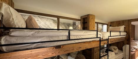 A bunk bed room with wooden walls, a stone wall, and a window.