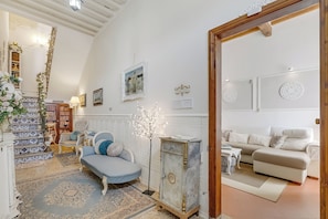 Ein Wohnzimmer mit Sofa, Schrank, Treppe und Bücherregal.