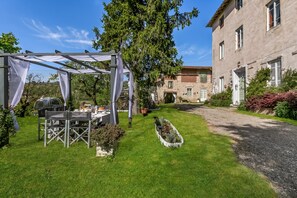 A covered outdoor dining area with a table and chairs, a pergola, and a building with a stone facade in the background. - Villa Mon Paradis 15 Garden Hot Tub Pet Friendly (Lucca)