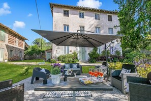 An outdoor patio with seating, a table with drinks, and a large umbrella. - Villa Mon Paradis 15 Garden Hot Tub Pet Friendly (Lucca)