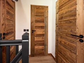 Ein Korridor mit Holztüren, einem schwarzen Metallgeländer und einer weißen Wand.