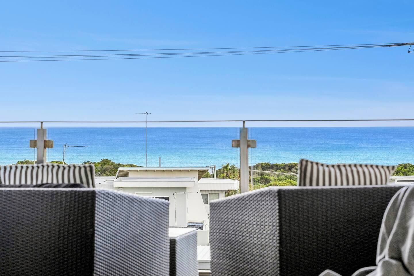 A balcony with wicker chairs and a view of the ocean.