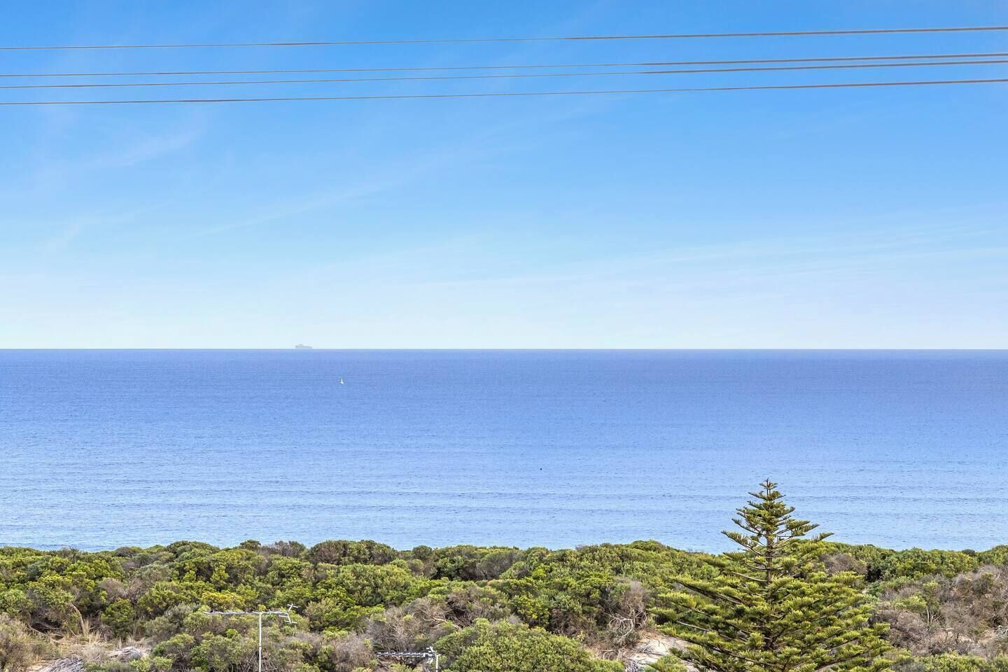 A coastal landscape with dense greenery and a clear view of the sea.