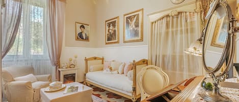 A classic bedroom with a bed, a chair, a desk, and a mirror.