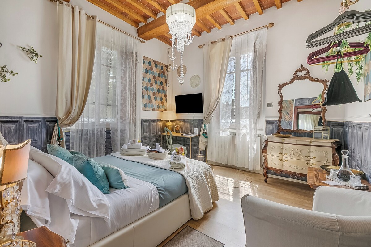 Ein Schlafzimmer mit einem Bett, einem Schminktisch, einem Spiegel, einer Chandelier und einem Fernseher.