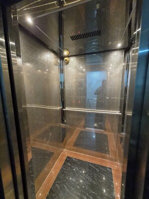 Un ascensor con paredes metálicas y baldosas decorativas en el suelo.