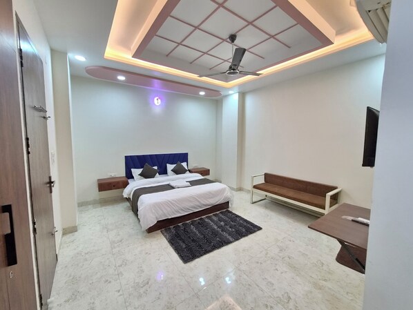 A modern bedroom with a bed, bedside tables, a bench, and a ceiling fan. - Hotel Delight (Jaipur)