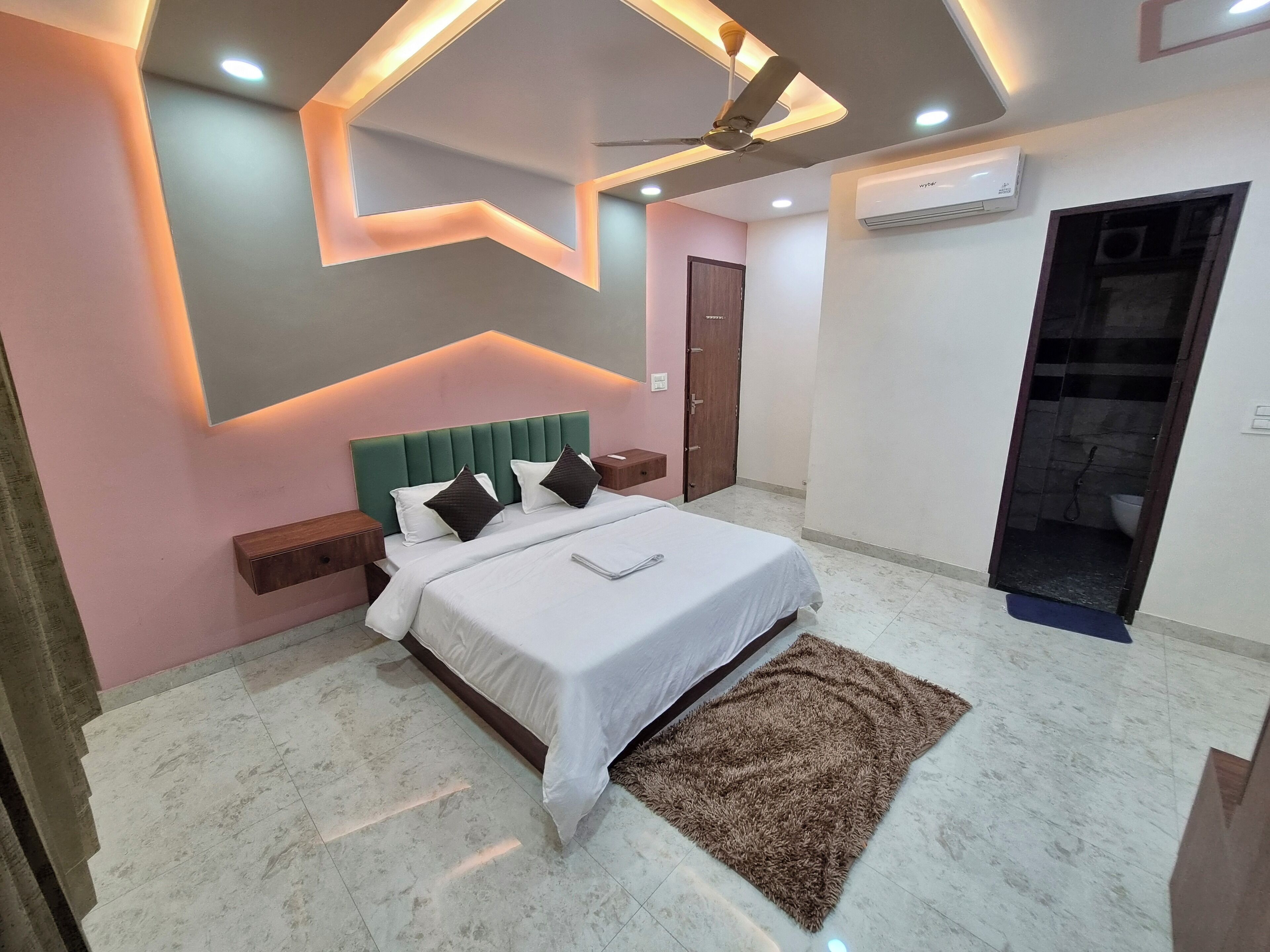A modern bedroom with a bed, nightstands, a ceiling fan, recessed lighting, and an air conditioning unit.