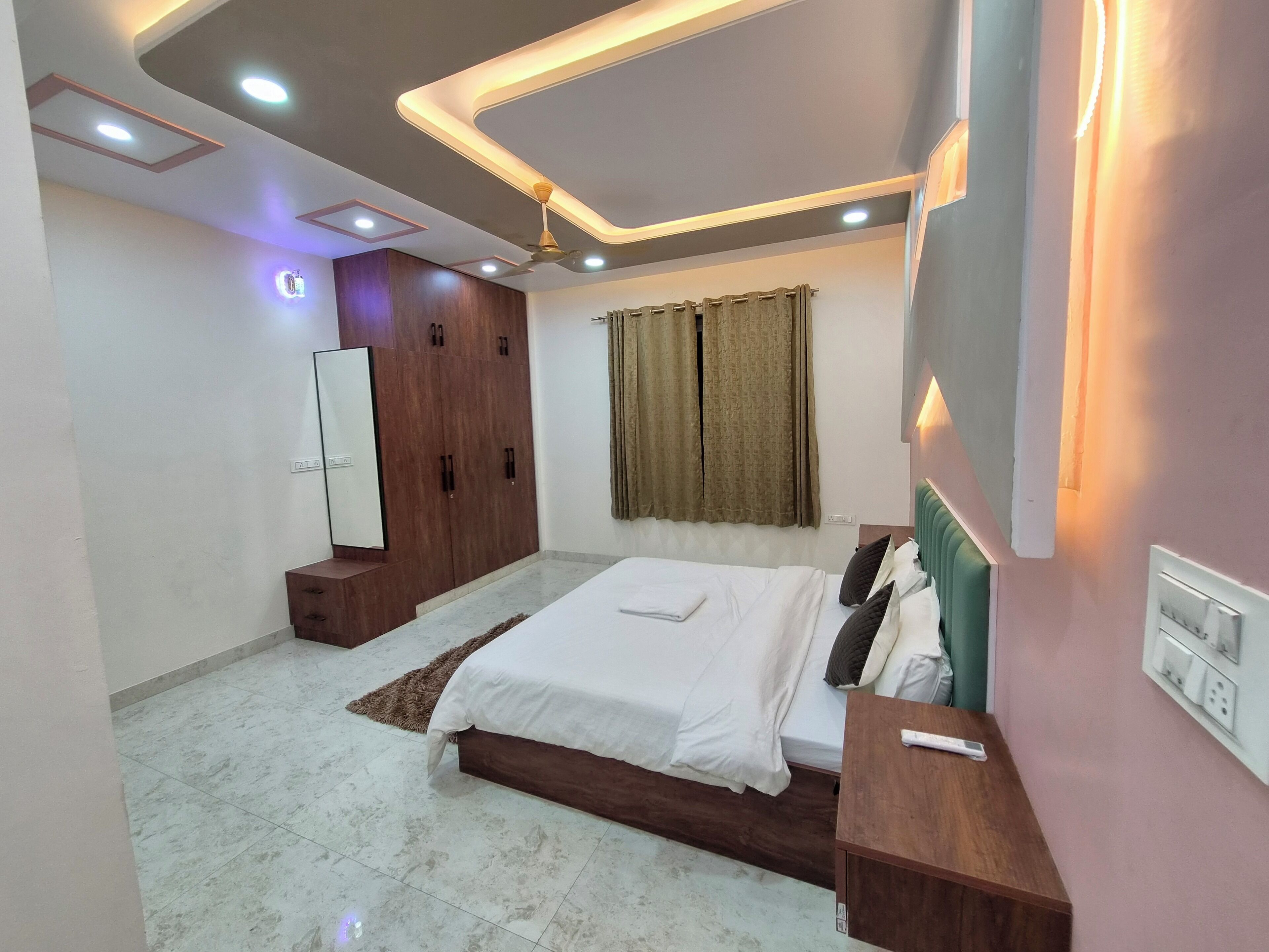 A modern bedroom with a bed, bedside table, wardrobe, and a ceiling light fixture.