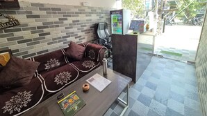 Zona de recepción con sofá, mesa de centro, carta y cartel que enumera servicios como habitaciones, sala de estar y piscina.