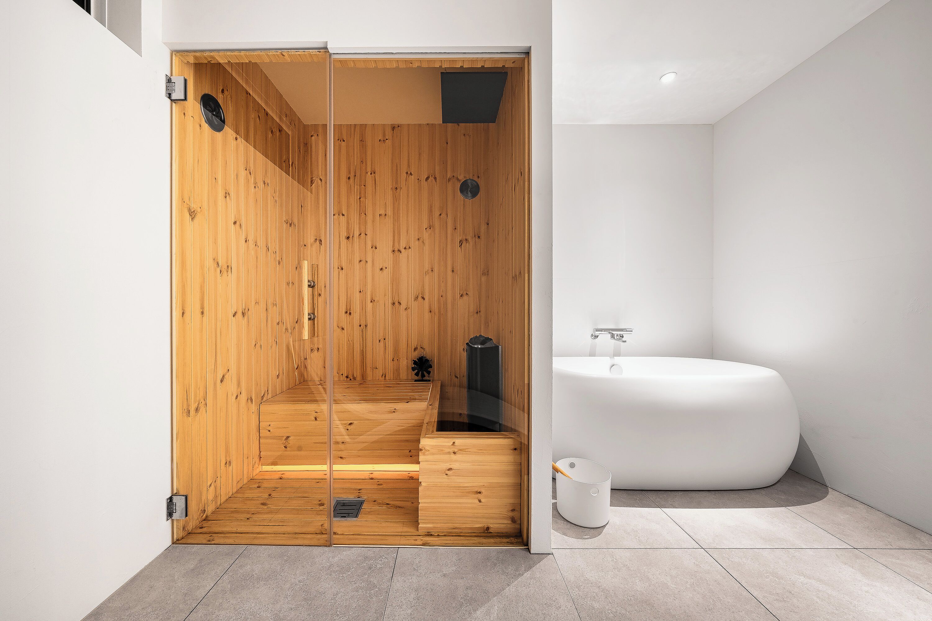 A modern bathroom with a wooden shower enclosure, a white bathtub, and a minimalist design.