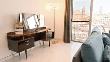 Ein modernes Zimmer mit Schreibtisch, einem großen Spiegel, einer Stehlampe und einer Couch.
