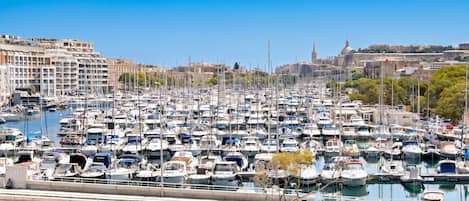 A marina filled with numerous boats docked in a harbor with buildings in the background.