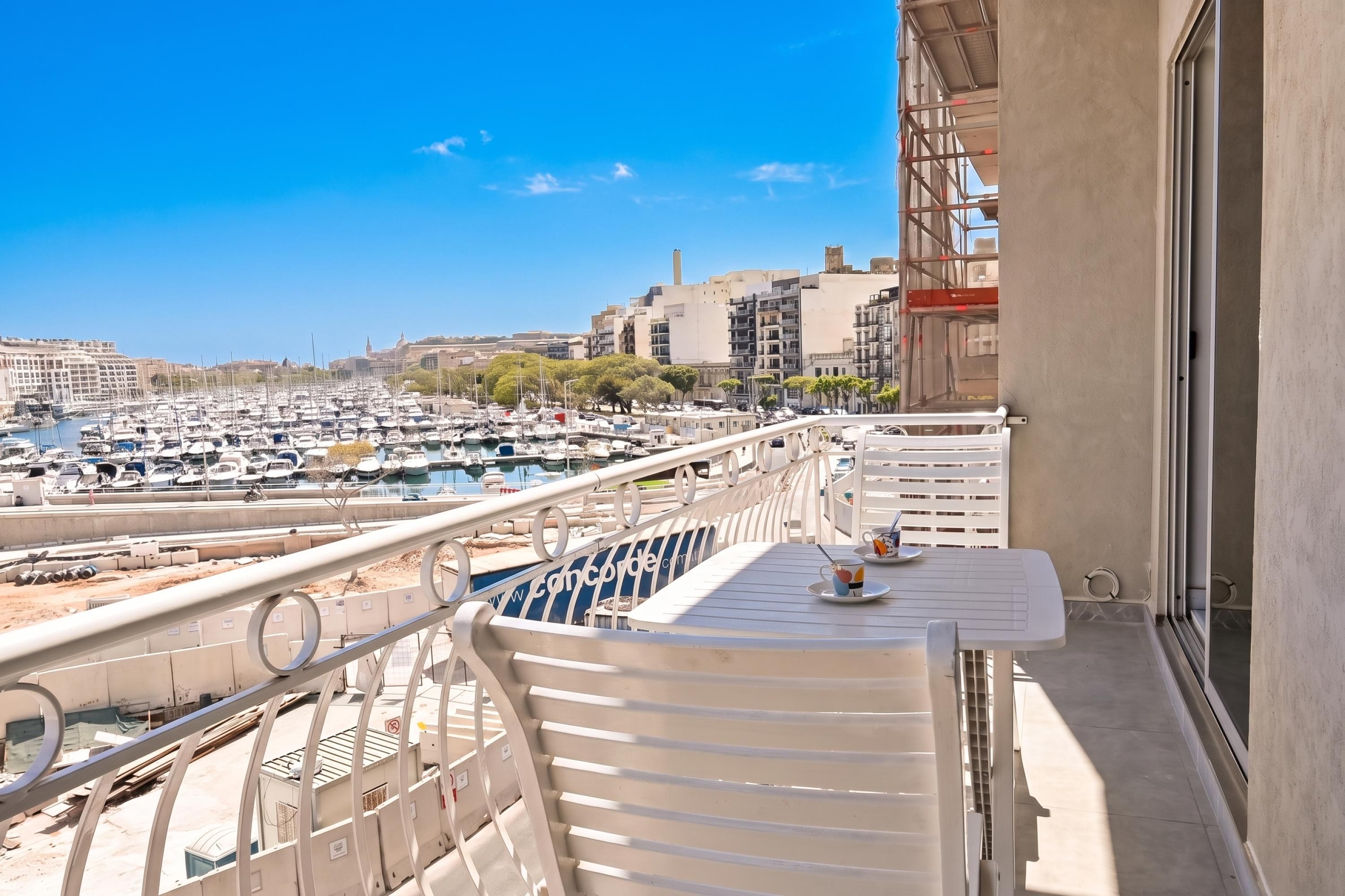 A balcony with a view of a marina and cityscape.